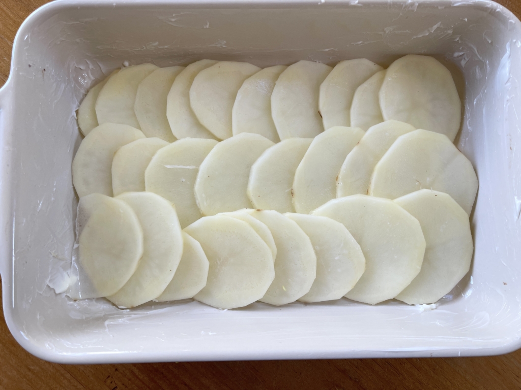 Then place one-third of the potato slices into the pan slightly overlapping them until bottom of dish is covered. 