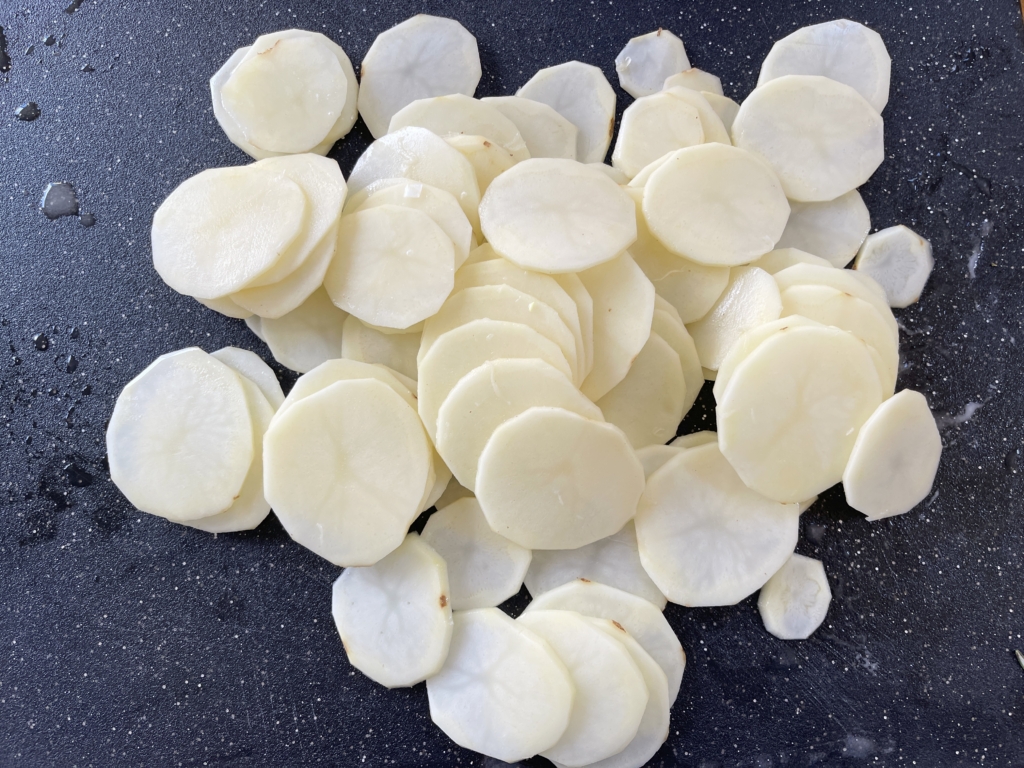 While onions are cooking, slice the potatoes info rounds, preferably using a mandolin. Cover the potatoes with a damp cloth or paper towel to keep them from browning.
