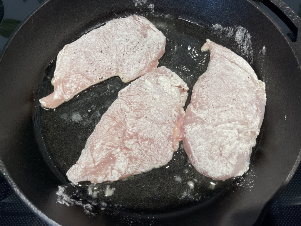 Heat oil on medium heat in a large cast iron skillet (or large stovetop to oven pan). Once oil is heated, carefully add three of the breasts to the pan. Cook for 3 minutes.