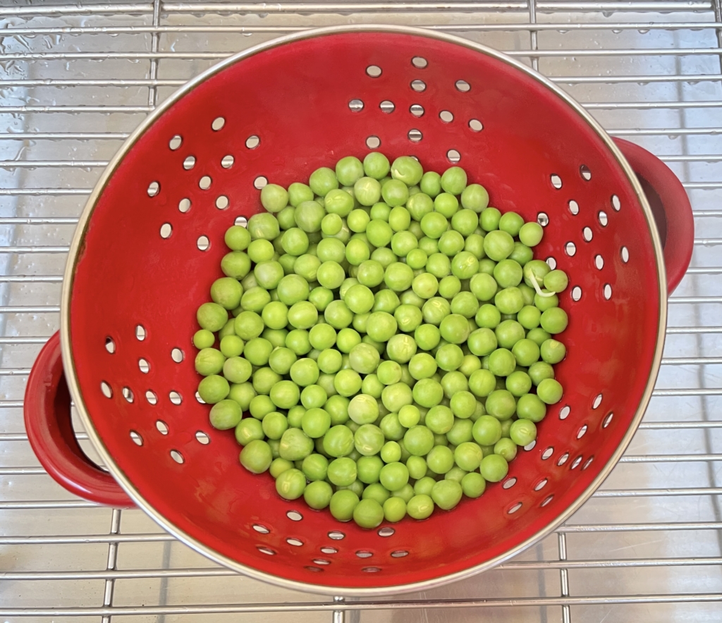 Pour peas into a strainer or colander (a slotted spoon could also be used).