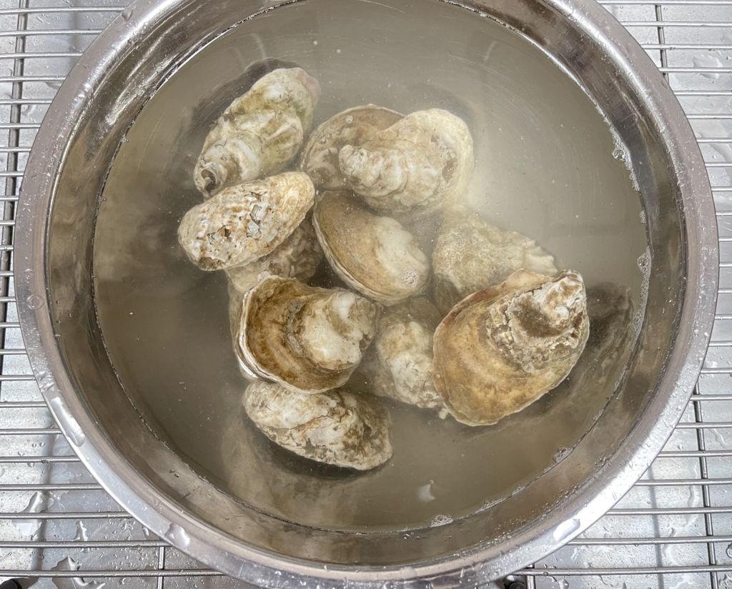 Before grilling, you’ll want to clean the oysters, it’s easy:
Fill a medium-sized bowl with cold tap water and 2 teaspoons of kosher salt and mix them together
Gently place the oysters into the bowl.
Let sit for 1/2 hour, gently stirring the oysters every 10 minutes to help agitate them which promotes the release of any sand or dirt inside the oyster.