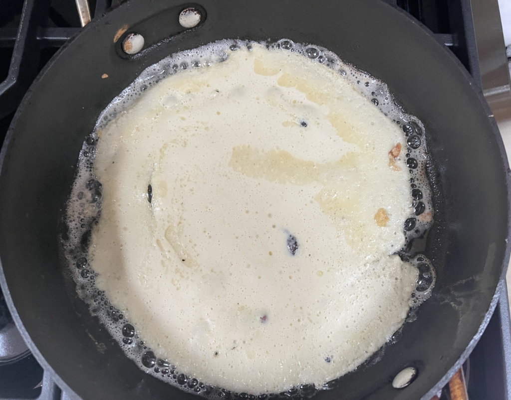 Once the butter/oil is heated, add 1/3 of crepe batter to the pan, and gently swirl the pan in a circular motion to spread the batter. Cook the first side for approximately 1 minute or until the edges and bottom side has browned spots.